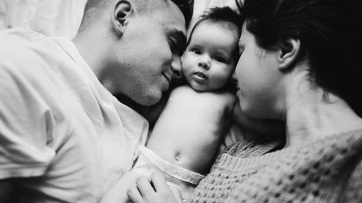 A touching black and white portrait capturing a family moment with a baby embracing parents.